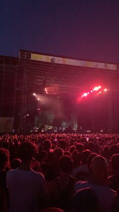 a large crowd at a concert with bright lights on the stage and in the dark