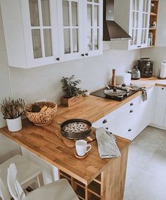 a kitchen with white cupboards and wooden counter tops, along with a potted plant