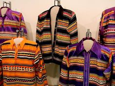 several colorful jackets are hanging on the wall next to each other, with one jacket open