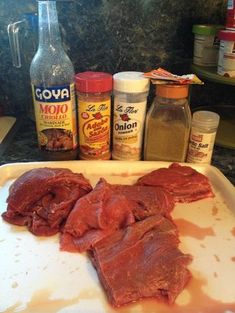 raw meat on a cutting board next to spices and seasonings