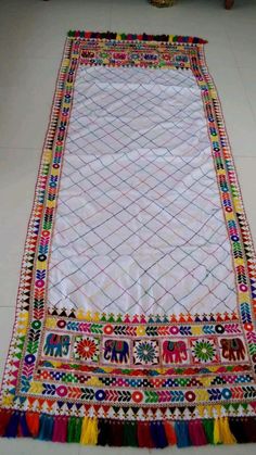 a multicolored rug on the floor with an elephant design and tassels