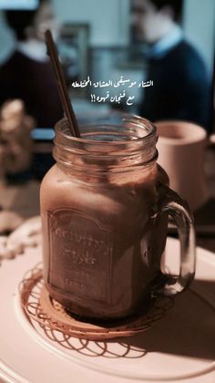 a mason jar filled with liquid sitting on top of a white plate next to a cup