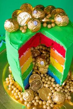 a rainbow cake with gold coins and candy on the top, sitting on a green plate