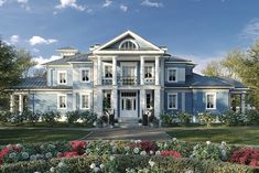 a large blue house with white trim on the front and side windows is surrounded by flowers