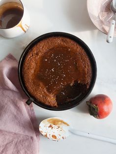 a table topped with a bowl of cake next to a cup of coffee and an apple