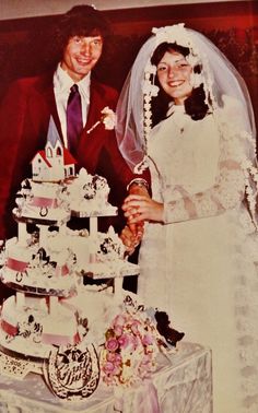 a bride and groom standing next to a wedding cake