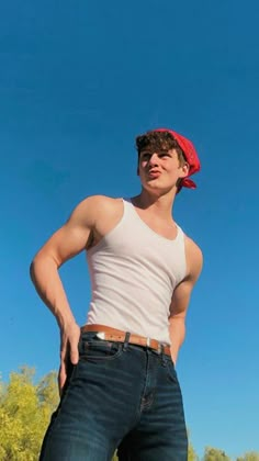 a young man in jeans and a red bandana poses for the camera with his hands on his hips