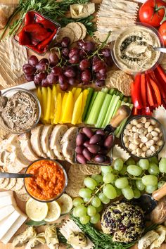 a platter filled with different types of cheeses, crackers and vegetables on a wooden table