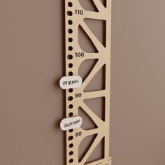 a wooden ruler with numbers on it hanging from the side of a wall in front of a brown wall