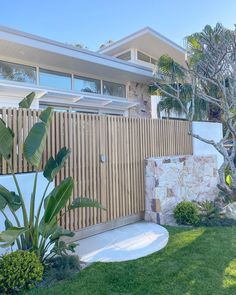 a house that is next to a tree and some grass in front of the fence