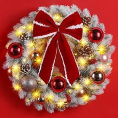 a christmas wreath with red and white ornaments on it, surrounded by pine cones and lights