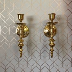 two golden candlesticks are next to each other against a wallpapered background