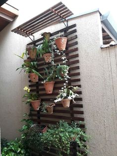 several potted plants are hanging on the side of a building with wooden slats