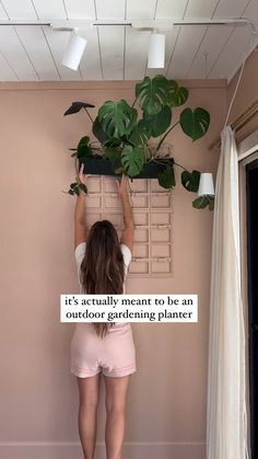 a woman holding up a potted plant in front of a pink wall with the words it's actually meant to be an outdoor gardening planner