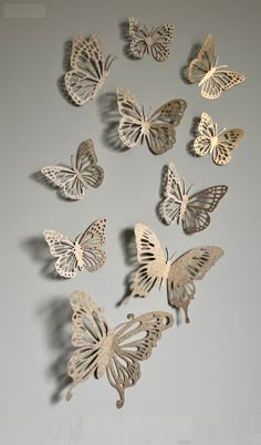 a group of butterflies flying in the air on a gray wall with white walls behind them