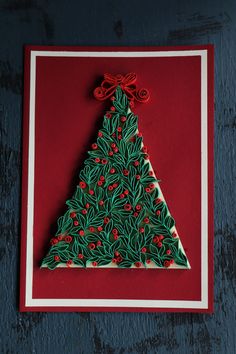 a christmas tree made out of paper on a red and white card with holly berries