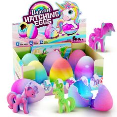 an assortment of hatch eggs in a box with unicorn figurines next to it