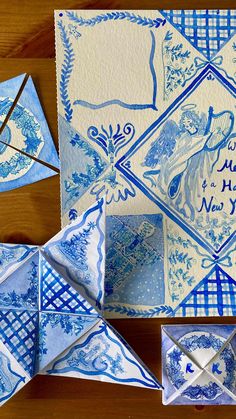 blue and white paper folded in squares on a wooden table next to origami pieces