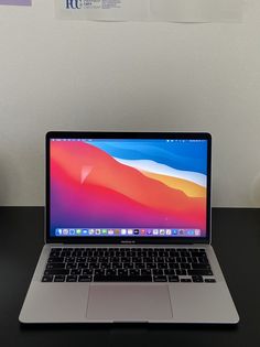 an open laptop computer sitting on top of a black desk next to a white wall