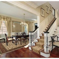 a staircase leading up to a formal dining room with chandelier and wooden floors