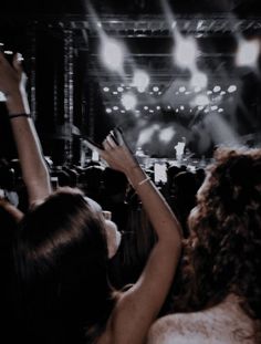 two women at a concert raising their hands in the air