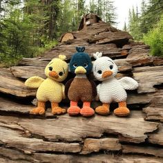 three crocheted stuffed animals sitting next to each other on top of a log