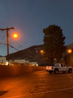 a white truck parked on the side of a road next to a wooden fence at night