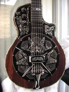 a black and white guitar with skulls on it's back, in front of a window