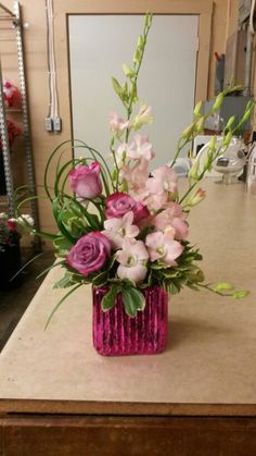 a pink vase filled with flowers on top of a counter