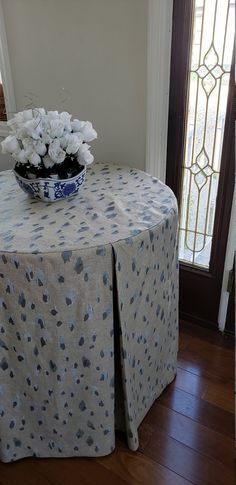 a vase with white flowers sitting on top of a table next to a door and window