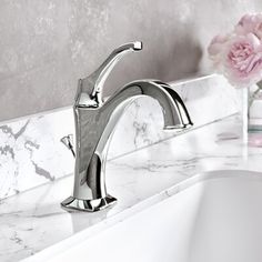 a bathroom sink with a marble counter top and white porcelain wall behind the faucet