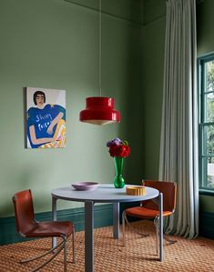 a dining room with green walls and a painting hanging on the wall next to a round table