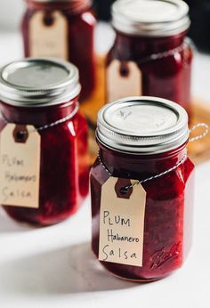 four jars filled with jam sitting on top of a table