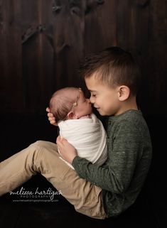 a young boy is holding his newborn sibling