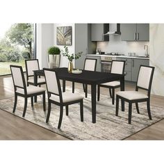 a black and white dining room table surrounded by beige upholstered chairs with an area rug on the floor