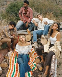 several people sitting on the ground with blankets around them