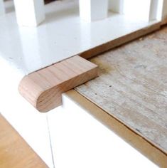 an unfinished piece of wood sitting on top of a white cabinet door with a wooden handle