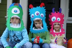 three children in monster costumes sitting on the front porch with their mouths open and teeth out