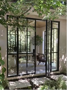 an open glass door leading into a patio area with chairs and trees in the background