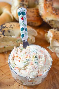 a small glass bowl filled with cream cheese and sprinkles next to bagels