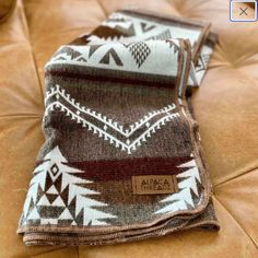 a brown and white blanket sitting on top of a couch