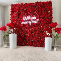 red flowers in vases next to a wall that says will you marry me?