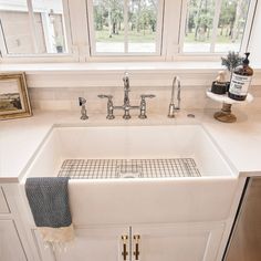 a white kitchen sink sitting under a window next to a counter top with two faucets