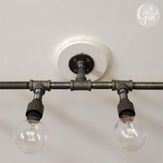 three light bulbs are attached to an industrial style track lighting fixture in a white room