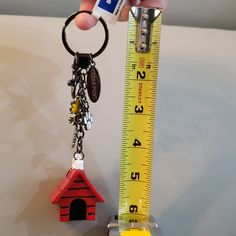 a person holding a measuring tape and a house shaped keychain