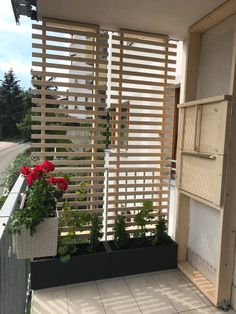 a balcony with flowers and plants on the outside, in front of a wooden slatted wall