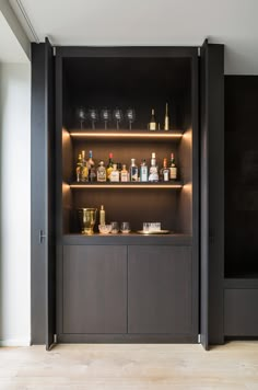 an open cabinet with bottles and glasses on it