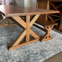 a wooden table sitting on top of a rug next to a book shelf and cabinet