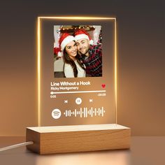 a light up photo frame with a christmas theme on the front and an image of a man and woman in santa's hats