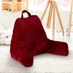 a red bean bag sitting on the floor next to a white teddy bear